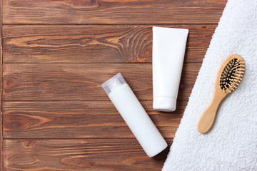 Obraz premium natural hair care products, hairbrush and towel on a wooden background top view. Shampoo, mask, balm. flatlay