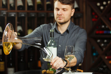 Sommelier pours white wine from decanter to the glass