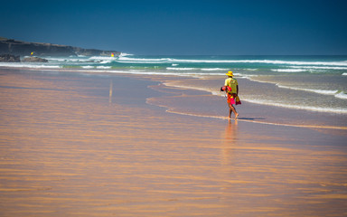 Lifeguard walking along beach on wild coast of Alentejo, Portugal
