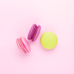 Pink, violet and green macarons on pink background. Top view.