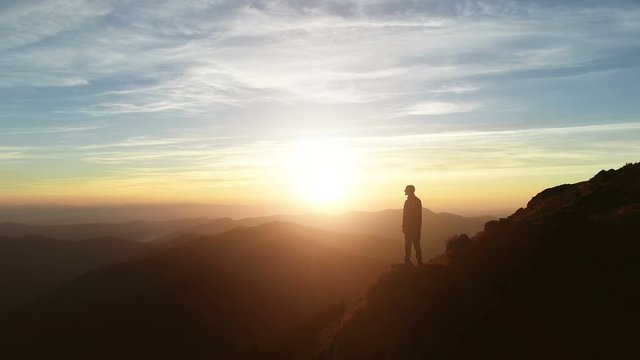 The male standing on the mountain and enjoying the sunrise
