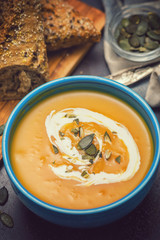 Homemade pumpkin soup served with cream and pumpkin seeds