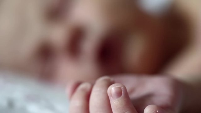 Newborn baby sleeps. Newborn two weeks old baby boy lies on the bed and sleeps. Little baby hand in the foreground