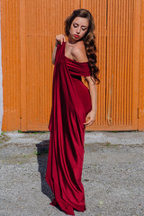 Beautiful young woman in a long red evening gown with a train