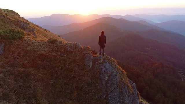 The man standing on the cliff and enjoying the sunrise