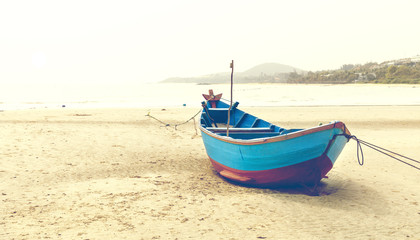 Fototapeta na wymiar Blue fishing boat on sandy beach in Vietnam