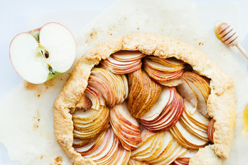 Apple and pear tasty galette with honey on the table. Open autumn pie, top view.