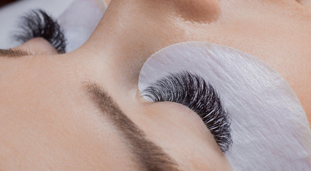 Woman with long eyelashes in beauty salon. Lashes extension procedure close up.