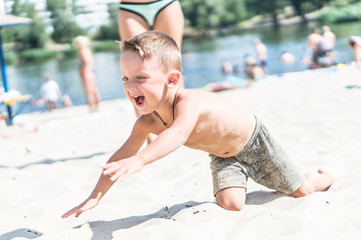 Smiling little baby boy playing in the sand