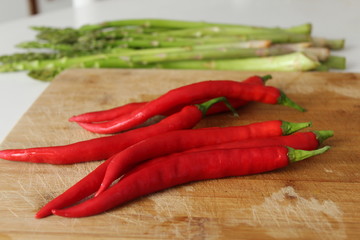 Red chili peppers close up and asparagus on chopping board