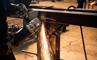 Worker grinding metal with angle grinder