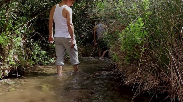Two people walk on water near a river in Algerian forest, Tlemcen on a sunny day