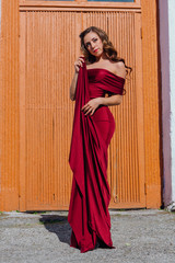 Beautiful young woman in a long red evening gown with a train