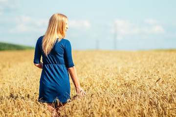 Beautiful woman walking in wheat field.