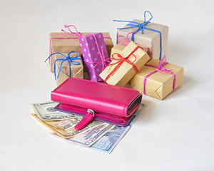 The wallet, dollars and packed gifts on the light background, selective focus.