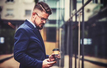 Young business man drinking coffee and using digital tablet outdoor. Business, education, lifestyle concept