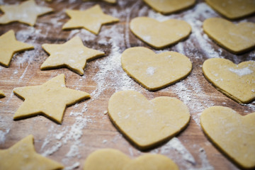 Christmas baking. Making gingerbread biscuits. Cookie dough in heart and star shape on kitchen counter.