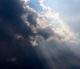 The sun rays in the sky though the rain clouds.