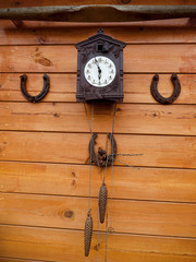 Antique Cuckoo wall clock and weights hanging on a wooden background. Horseshoe for luck. rustic decor..