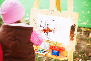 little girl draws  on the easel. the child paints