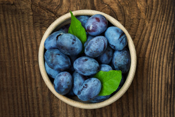 Fresh blue plums on wood table background. Sweet autumn fruit. Delicious and healthy raw food full of vitamins.