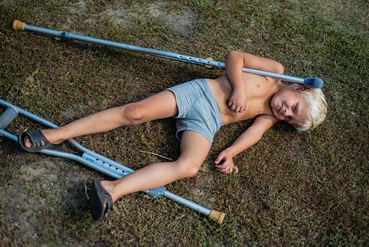 Boy shirtless with his crutches fell to the ground