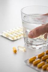 Frau nimmt gelbe Kapsel Tabletten  aus Pillen Blister mit Wasser Glas