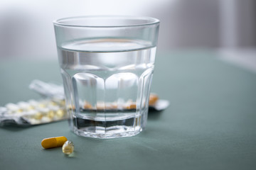 Zwei Gelbe Pillen Kapsel Medikament und Blister mit Glas Wasser