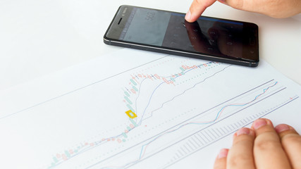 Closeup image of businesman using calcualtor to analyse stock sales graph