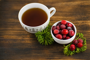Cranberry tea in a cup on a wooden background. Cranberry tea and berries on a wooden surface.