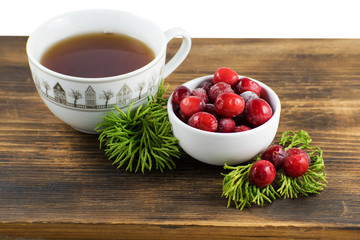Cranberry tea in a cup on a wooden background. Cranberry tea and berries on a wooden surface.