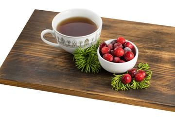 Cranberry tea in a cup on a wooden background. Cranberry tea and berries on a wooden surface.