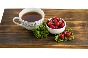 Cranberry tea in a cup on a wooden background. Cranberry tea and berries on a wooden surface.