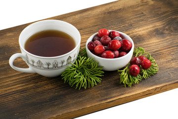 Cranberry tea in a cup on a wooden background. Cranberry tea and berries on a wooden surface.