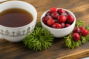 Cranberry tea in a cup on a wooden background. Cranberry tea and berries on a wooden surface.