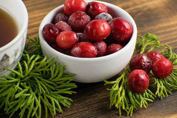 Cranberry tea in a cup on a wooden background. Cranberry tea and berries on a wooden surface.
