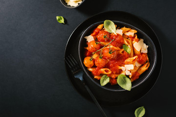 Tasty tomato pasta in bowl on dark