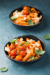 Tasty tomato pasta in bowls on blue table