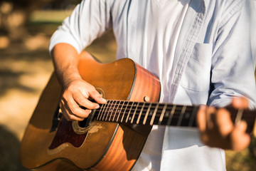 Fototapeta premium Young handsome asian man playing guitar in park. Outdoor lifestyle.