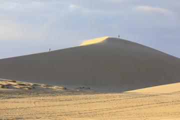 Tourist walk on yellow sand dunes in Mui Ne, Vietnam
