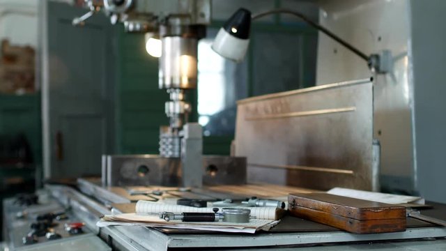 A private workshop for working with metal parts, in the background a drilling machine drills a hole in the pulley, on the table lie measuring tools, production
