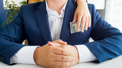 Closeup photo of female hand taking money from businessman's pocket