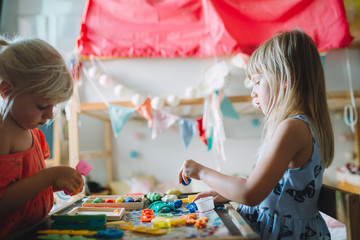 Fototapeta premium two little girls playimg with play dough at home