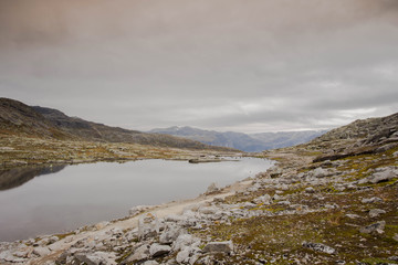 Rugged dramatic mountain landscape in norway cloudy dramatic day with calm lake