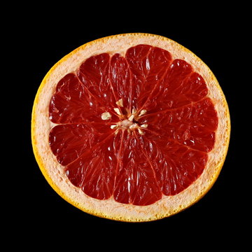 Grapefruit slice isolated on black background, top view