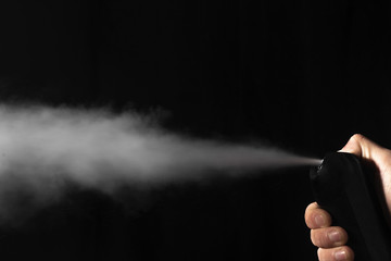 Man spraying deodorant on dark