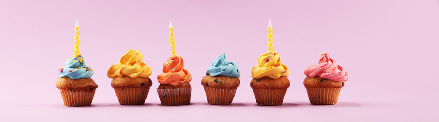 Tasty cupcakes on pinke background. Birthday cupcake in rainbow colors.