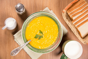 Pumpkin cream soup in a green ceramic plate on the kitchen table