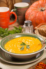 Pumpkin cream soup in a green ceramic plate on the kitchen table