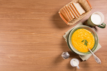 Pumpkin cream soup in a green ceramic plate on the kitchen table